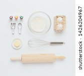 Small photo of Baking tools and ingredients: flour and eggs, butter, food dyes, rolling pin, whisk, cookie cutters, kitchen cloth and seashells somehow. Top view.