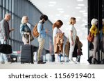 Side view of multiracial people standing in queue to check in in airport hall