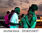Happy young African couple dancing against their friends at rooftop party