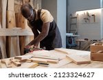 Portrait of mature black man building wooden furniture in carpentry workshop, copy space