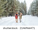Small photo of Happy African American man, his wife and son having stroll in fresh air on frosty winter day among coniferous trees covered with snow