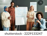 Small photo of Several happy young intercultural students and mature blond teacher surrounding whiteboard with explanation of Present Simple tense