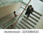 Small photo of Above view of multicultural white collar workers in formalwear moving downstairs inside modern business center while leaving after work