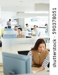 Small photo of Separate workplace cubicles with different people sitting at them in open space of modern office