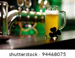 Image of glass of beer with shamrock leaf on pub table