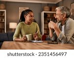 Two experienced individuals are deep in conversation while enjoying a comforting drink at their home table.