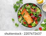 Small photo of Grilled salmon fish fillet and fresh green leafy vegetable salad with tomatoes, red onion and broccoli. Healthy food. Ketogenic lunch. Top view