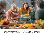 Thanksgiving Day, Autumn feast. Happy family sitting at the table and celebrating holiday. Grandparents, mother, father and children. Traditional dinner.