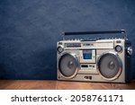 Small photo of Retro boombox ghetto blaster outdated portable radio receiver with cassette recorder from 80s front concrete black wall background. Rap, Hip Hop music concept. Vintage old style filtered photo