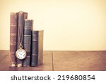 Old vintage books and pocket watches on wooden desk. Retro style filtered photo