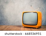 Retro old orange TV receiver on table front textured concrete wall background. Vintage style filtered photo