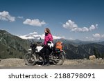 Portrait of beautiful female motorcyclist sitting on motorcycle on top of mountain. Dangerous mountain road in moto trip