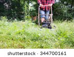 Weekend warrior hacks through a field of weeds, trying to get the lawn back under control at the cottage, using an ancient old lawnmower