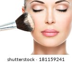 Closeup portrait of a woman  applying dry cosmetic tonal foundation  on the face using makeup brush. 