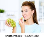 beautiful woman eating  grapes is on the kitchen