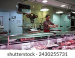 Small photo of Barcelona, Spain – April 18, 2018: Horizontal view of a butcher in his butcher’s stall in the old Abaceria Central Market of the Gracia neighborhood