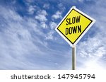 Slow Down yellow road sign on blue sky with clouds background