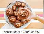 Indulgent Tiramisu Doughnut Held by woman's hand Indoors at a bakery.