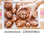 Indulgent Tiramisu Doughnut Held by woman's hand Indoors at a bakery.