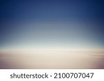 Small photo of The of a clear blue sky with a very flat featureless cloudy sky below as viewed from the window of a jet.