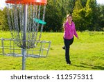 Woman throwing a disc to the disc basket
