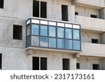 Small photo of One glazed balcony in an unfinished block high-rise building.