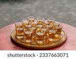 Small photo of Small glasses filled with brandy on a wooden tray. Alcoholic buffet in street cafe. Shots with alcoholic beverage for taste.