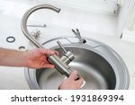 Close-up plumber hands holds a new faucet for installing into the kitchen sink, plumbing work or renovation