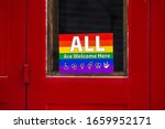 Small photo of The LGBT community stickers "All are welcome here" on the door in the old city in a sign of friendly neighborliness and hospitality for all types of gender people. somewhere in some city in Spain.