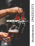 Small photo of bartender hand at beer tap pouring a draught beer in glass serving in a restaurant or pub