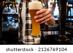 Small photo of bartender pouring a draught beer in glass serving in a bar or pub