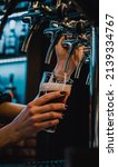 Small photo of bartender woman hand at beer tap pouring a draught beer in glass serving in a restaurant or pub