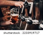 Small photo of bartender hand at beer tap pouring a draught beer in glass serving in a bar or pub. tap room