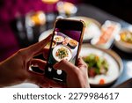 hand with smartphone photographing food at restaurant or cafe