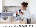 Online mobile shopping in pharmacy store. Ill female with phone, bank credit card make internet purchase using web banking system. Sick woman entering payment information in smartphone application.