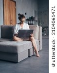 Small photo of Woman sits at home on the couch in a nightgown with a laptop