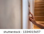 Small photo of Close up of Asian Woman right hand is turning on or off on light switch over wooden stair background. Copy space.