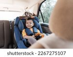 Cheerful smiling Asian little boy in safety car seat, Happy small child travel by car with family.