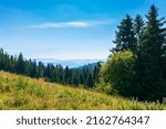 Small photo of countryside summer landscape in mountains. beautiful nature scenery with forested hills and grassy hills. green outdoor environment beneath a blue sky at high noon