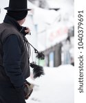 Small photo of Side view of chimney sweeper with brooms on cold snowy day. Good luck concept