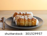 Sweet tubes filled egg white, Czech confection called Kremrole on gray plate on wooden table.