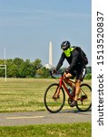 Small photo of Arlington, Virginia / USA - September 11, 2019: The Washington Monument and Jefferson Memorial in Washington, D.C. are seen as a man rides his bicycle at Gravelly Point Park on a hot summer day.