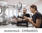 Small photo of Industrial Robotics program university students learning education mechanical assembly with Robot Universal Training Platform robot arm simulation model in engineering lab classroom.