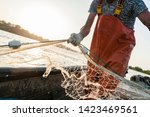 Small photo of Dynamic composition with a fisherman dressed in an orange rompers gathering his trammel net during a fishing trip on the Danube river.