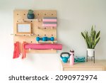 Workout fitness at home gym organized shelves for pilates equipment. Wood pegboard storing resistance bands, weights, yoga blocks, motivational message board. Women exercising at home.