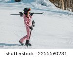 Winter Skiing. Ski portrait of woman alpine skier holdings skis wearing helmet, cool ski goggles, hardshell winter jacket and ski gloves on snow covered ski trail slope