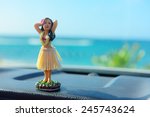 Hawaii road trip - car hula dancer doll dancing on the dashboard in front of the ocean. Tourism and travel freedom concept.