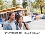 San Francisco city travel couple tourists people lifestyle. Young interracial students on city street looking away with cable car railway system in the background, popular attraction in San Francisco.