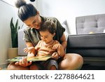 Small photo of Mom reading a book with baby boy at home. Early age children education, development. Mother and child spending time together. Candid lifestyle.