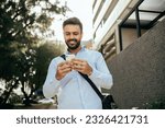 Small photo of A businessman striding through the city managing business matters on his cellphone